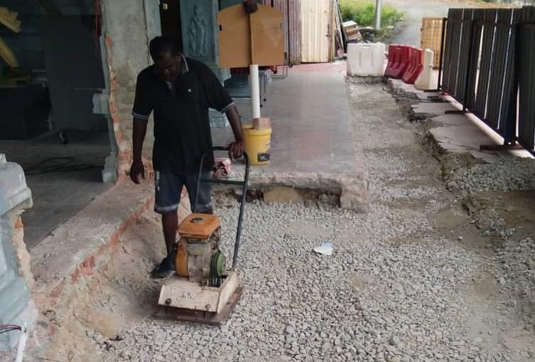 Worker power-floating a concrete floor slab inside a building