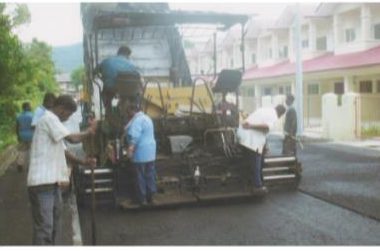 Workers and paving machine in front of completed terrace houses