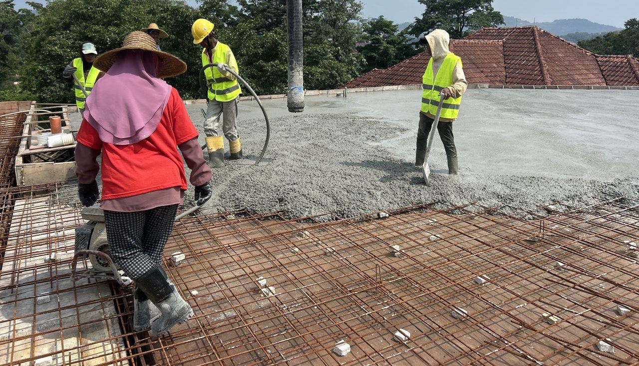 Workers levelling freshly placed concrete on a slab