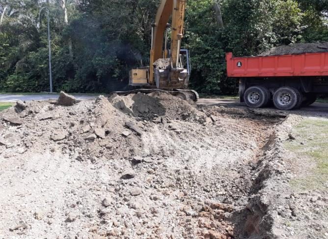 Excavator loading spoil into a tipper lorry during trench excavation