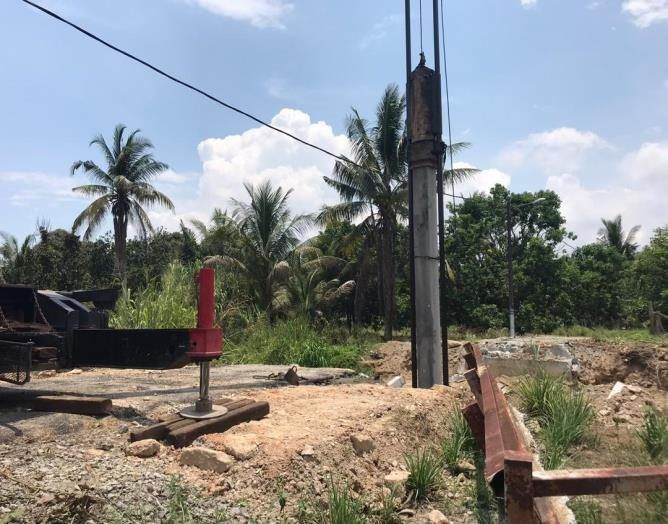 Steel sheet piles being driven along a river bank