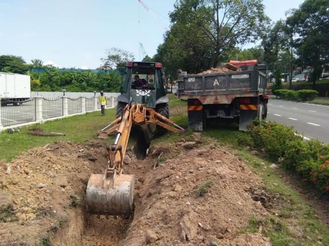 Backhoe loader and tipper lorry during road maintenance works