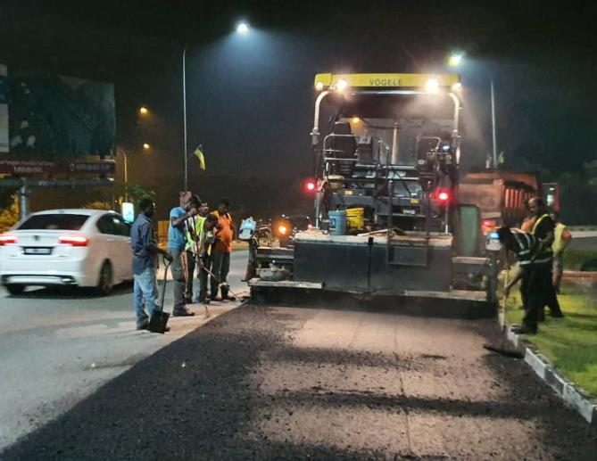 Night-time premix paving crew under lights